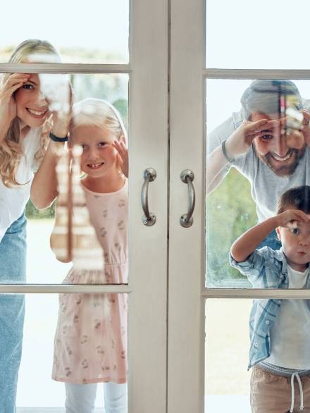 Curious couple with little kids standing and peering into their new home. Excited smiling caucasian.